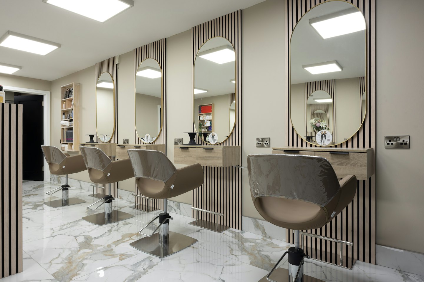 Leerer moderner Friseursalon mit Frisierplätzen und Marmorboden.