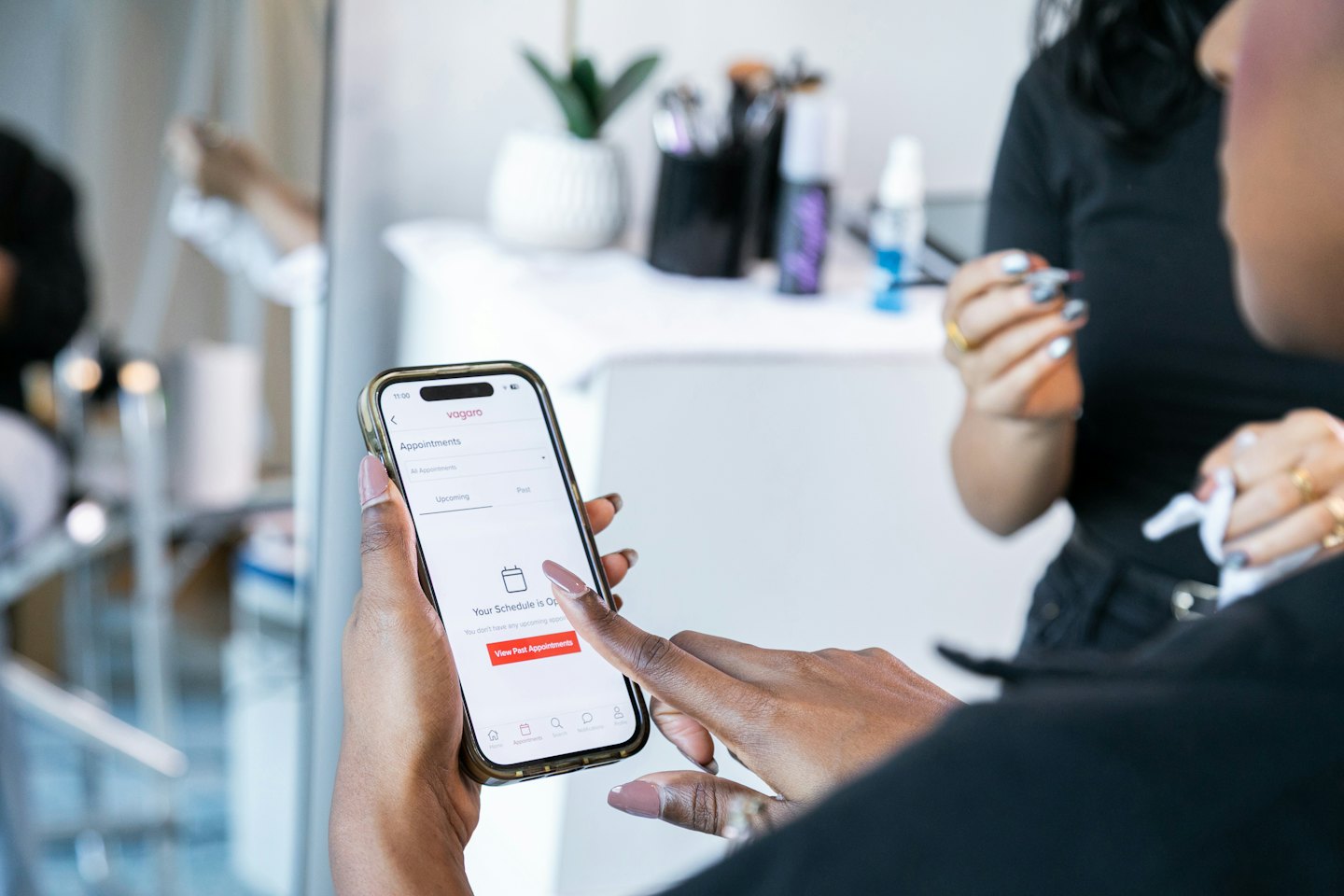 Frauenhände, die die Vagaro-App auf einem Smartphone-Bildschirm verwenden.